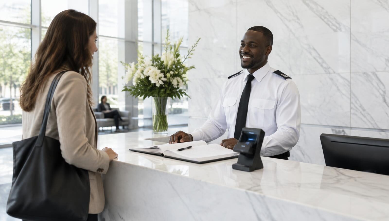 Security officer at a corporate reception desk checking in a visitor with a visitor register and ID scanner